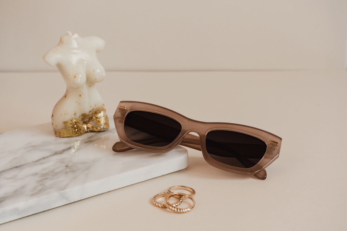 Brown Sunglasses with Jewelry on Beige Background
